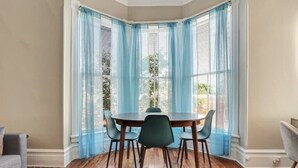 Un coin repas avec une table ronde, quatre chaises et des rideaux bleus.