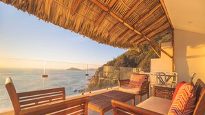 A wooden bench and table under a thatched roof, overlooking a coastal view with chairs and cushions. - Magical sunsets, king bed, and pro service B403 (Acapulco de Juárez)