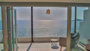 A balcony with a view of the sea, a hanging light fixture, and a chair with a cushion. - Magical sunsets, king bed, and pro service B403 (Acapulco de Juárez)