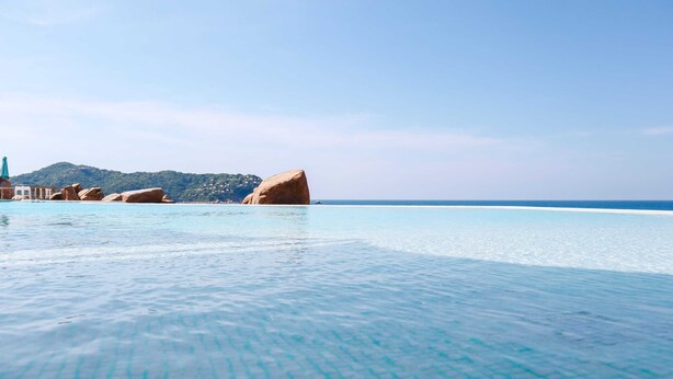 A clear blue pool with a tiled bottom, large boulders, and a distant mountain range. - Magical sunsets, king bed, and pro service B403 (Acapulco de Juárez)
