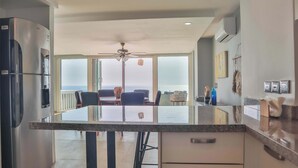 A modern kitchen with a large island, a built-in refrigerator, and a dining area with a view. - Magical sunsets, king bed, and pro service B403 (Acapulco de Juárez)