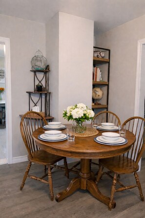 A dining table with six chairs, a vase with white flowers, and a globe on a shelf. - Mariner's Nest, Family- Friendly Costal Stay, 3BDR, Near Digby Ferry, Sleeps 5 (Saint John)