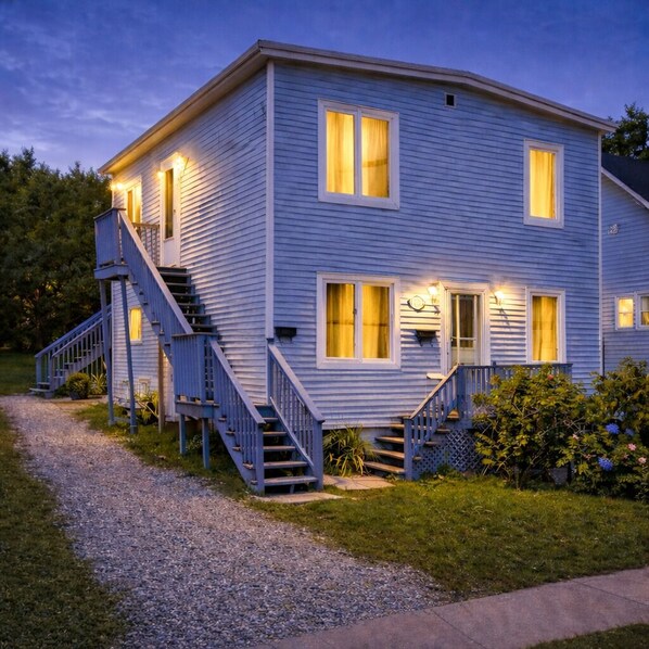 Ein zweigeschossiges Haus mit einer Treppe, einer Haustür und einem kleinen Veranda-Bereich.