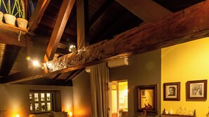 A cozy room with a bed, a sofa, and a dining table. There are potted plants and a mirror on the walls. - O Vilarejo Hospedaria e Gastronomia (Florianópolis)