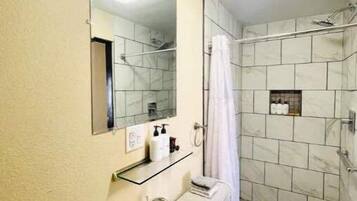 A bathroom with a sink, mirror, and shower.