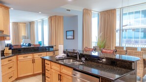 A modern kitchen with wooden cabinets, a stainless steel sink, and a large window with curtains. - Mediterranean 802E Beautiful-Gulf-front-4BR 4.5BA-Exquisite Views FloraBama (Pensacola)