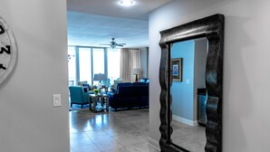 A spacious living room with a large mirror, a ceiling fan, and a view of the dining area. - Mediterranean 802E Beautiful-Gulf-front-4BR 4.5BA-Exquisite Views FloraBama (Pensacola)
