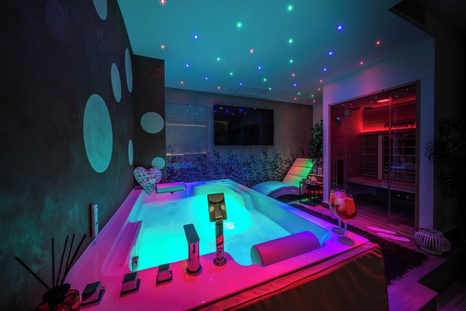 Un área de spa moderna con hidromasaje, iluminación ambiental y vistas al exterior.
