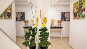 Une galerie d’art au décor moderne, où sont exposées des peintures abstraites et des plantes en pot.