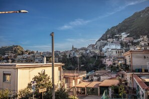 A coastal town with terracotta-roofed buildings, a prominent church spire, and a hillside with dense housing. - SUITE APARTMENT TAORMINA (Taormina)
