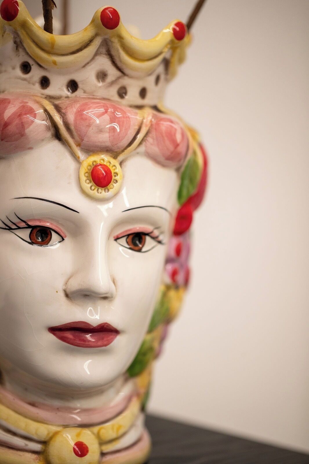 A ceramic sculpture with a crown, floral patterns, and a red gem.