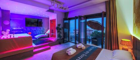A modern hotel room with a bed, a massage area, and a balcony with a view.