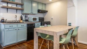 A compact kitchen with teal cabinets, a microwave, and a wooden dining table with chairs. - Unique Little Charmer in Downtown Frederick

 (Frederick)