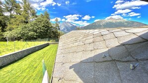 A stone roof with a view of a grassy area and mountains in the background. - Rilassante Baita con Giardino Recintato (Gignod)