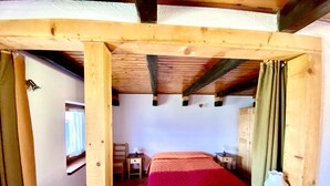 A wooden-framed room with a bed, a small table, and a chair. - Rilassante Baita con Giardino Recintato (Gignod)