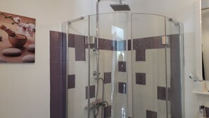 Enjoy a refreshing shower experience with a handheld and rain showerhead, set amidst a geometric tile pattern.