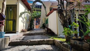 Un sendero estrecho que lleva a un edificio con una puerta verde numerada con el número 6.