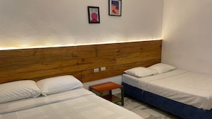 Habitación de hotel con dos camas, cabecera de madera, pequeño banco de madera y suelo de baldosas de mármol.