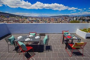 A rooftop terrace with tables and chairs, overlooking a cityscape. - Casa Alta (Quito)