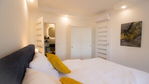 Un dormitorio con cama, armario, espejo y un cuadro en la pared.