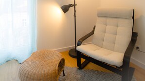 Una habitación moderna con una lámpara de pie, un sillón mullido y un pequeño reposapiés.