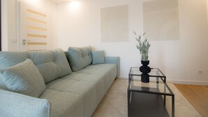 Una sala moderna con un sofá gris, una mesa de centro de vidrio y arte abstracto en la pared.