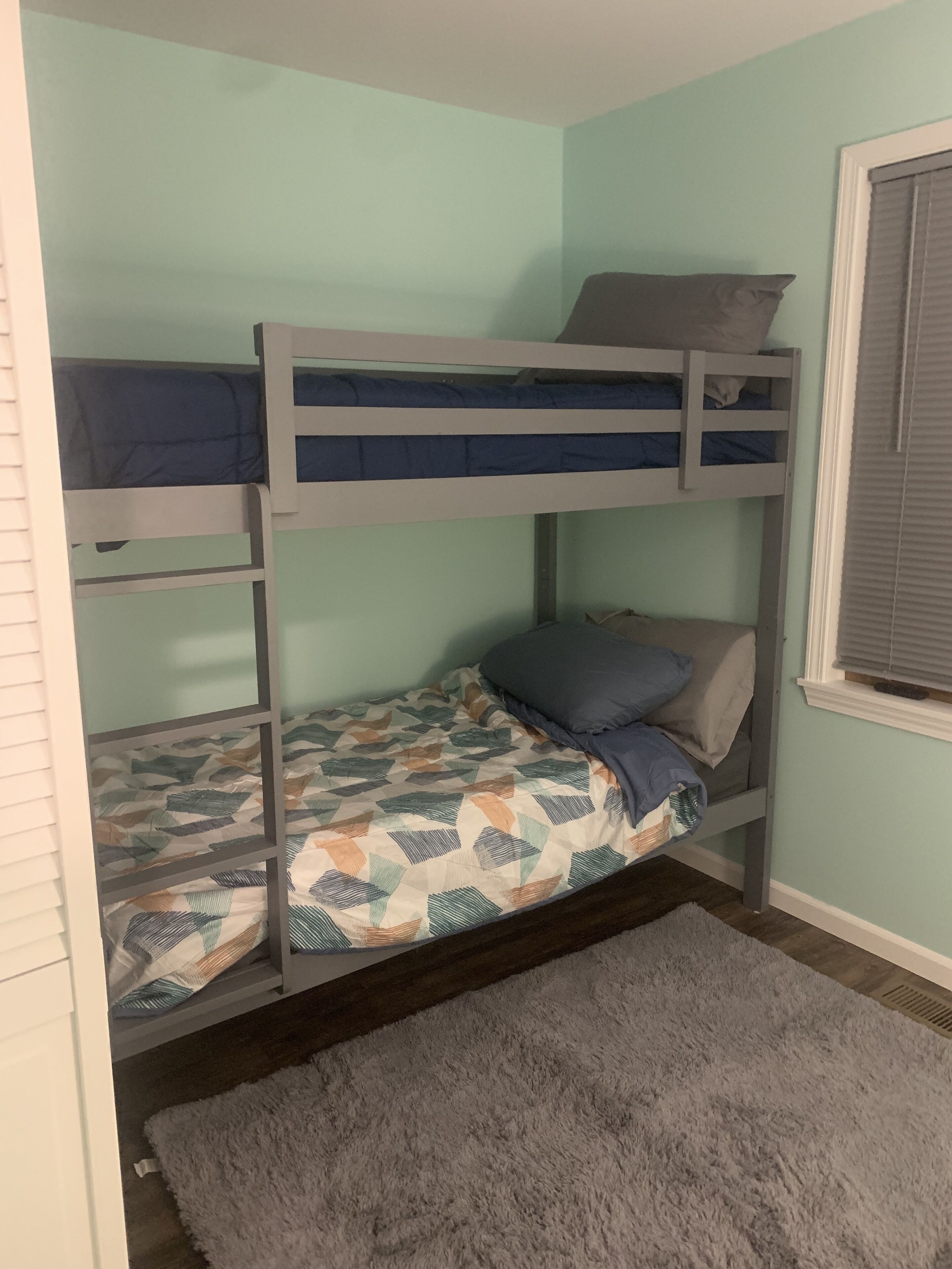 A bunk bed room with a patterned bedspread and a gray rug.