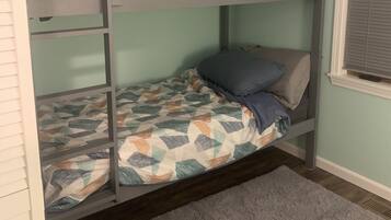 A bunk bed room with a patterned bedspread and a gray rug.