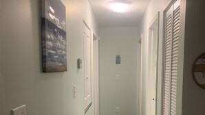 A narrow hallway with wooden flooring, white walls, and a ceiling light. - Cozy Lake House near Pymatuning Lake (Jamestown)