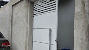 Une porte en métal blanche portant le numéro 30, une voiture garée devant, et une poubelle bleue.