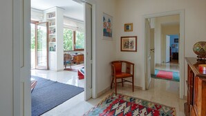 A spacious hallway with a wooden chair, a rug, and a bookshelf. - Parioli Luxury Terrace (Roma)
