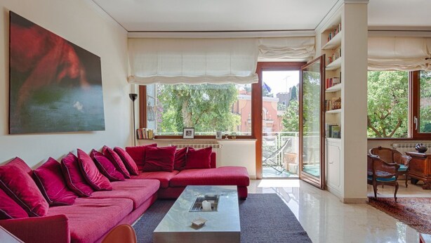 A modern living room with a red sofa, a coffee table, and a large painting. - Parioli Luxury Terrace (Roma)