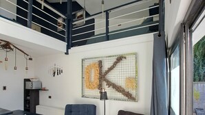 A spacious living area with a high ceiling, a dining table, two sofas, a coffee table, and a large window with curtains. - Okeyloft Coyhaique 2 (coyhaique)