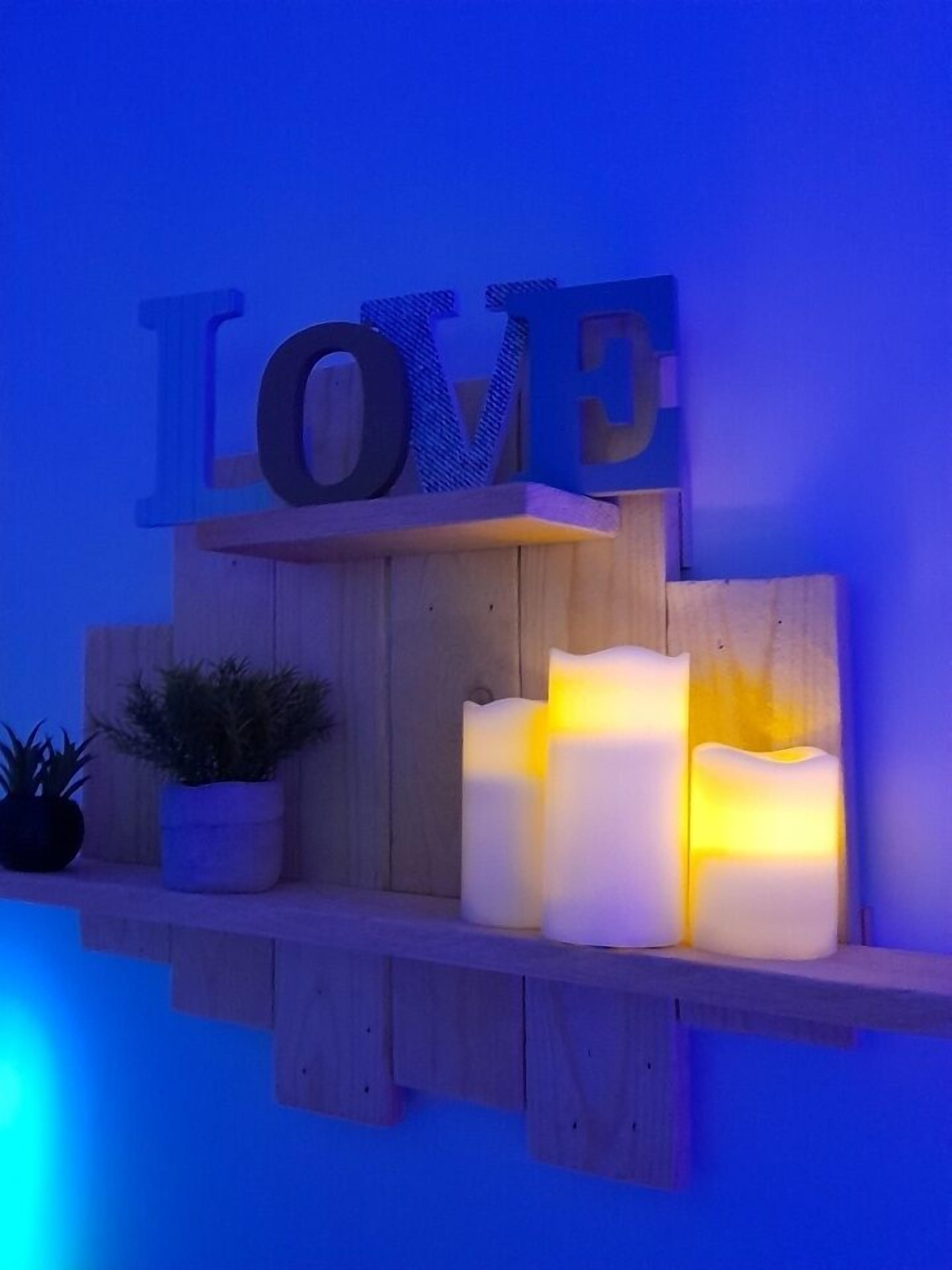 A wooden shelf with three lit candles and a 'LOVE' sign above them.