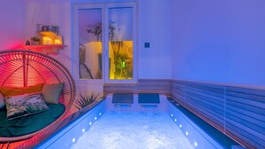Een moderne spa-ruimte met vloerverwarming, een gezellige zithoek met kussens en een raam met uitzicht op groen.