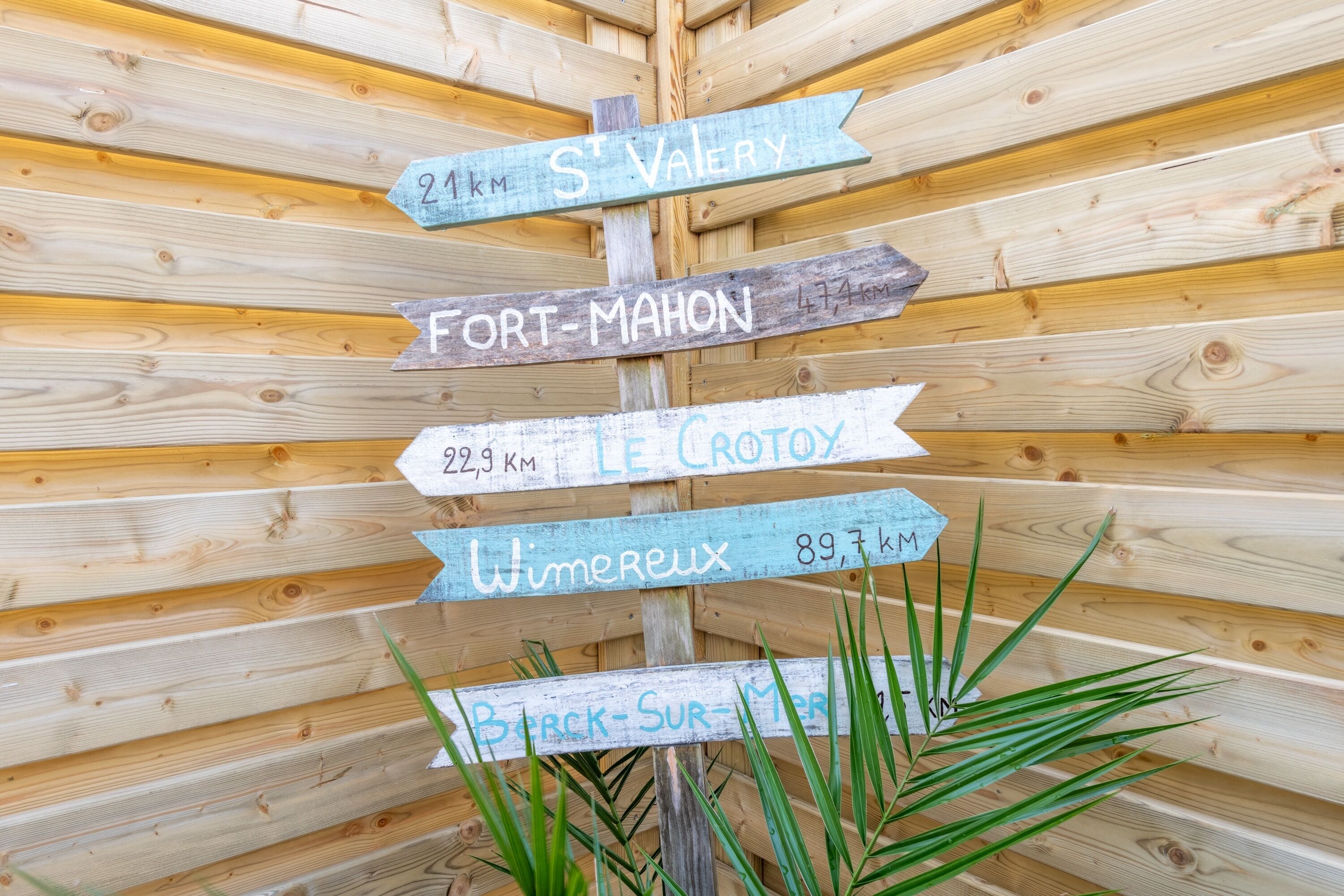 A wooden signpost with directional arrows and distances to various locations.