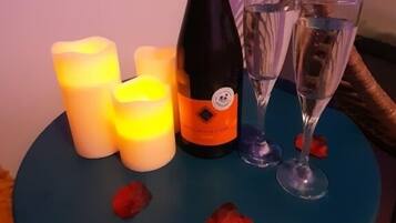 Una tavola con una bottiglia di champagne, due bicchieri e candele accese.