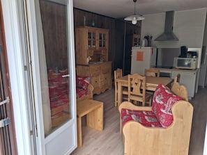 Um quarto acolhedor com uma mesa de jantar de madeira, cadeiras, um sofá, um armário e uma kitchenette.