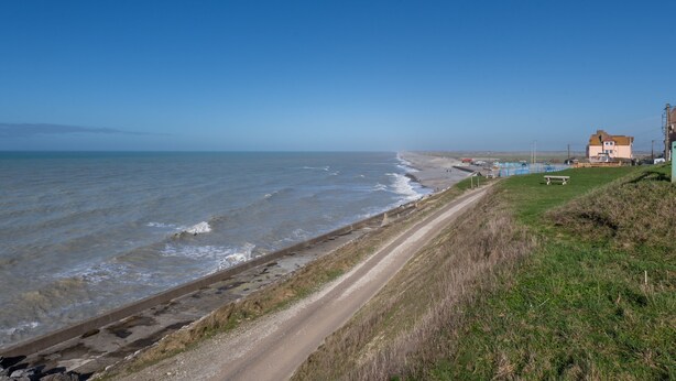 A coastal road with a beach on the right, a grassy area, and a building with a red roof. - L'Echappée Bleue - Appt pour 3 Vue mer latérale (Ault)