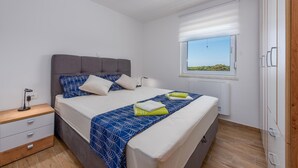 A bedroom with a bed, bedside table, and a window with a view.