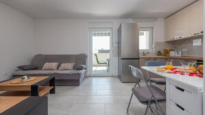 A compact living space with a sofa, a dining table, and a kitchenette.