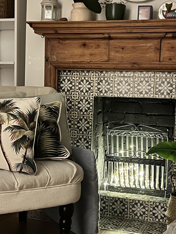 A living room with a sofa, a fireplace, and a patterned wall.