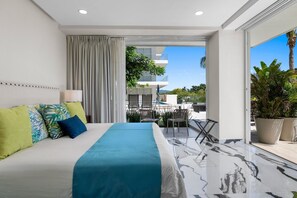 A modern hotel room with a large bed, a balcony with outdoor seating, and a view of the cityscape. - Quinta San Miguel alberca y playa 5 min (Nuevo Nayarit)