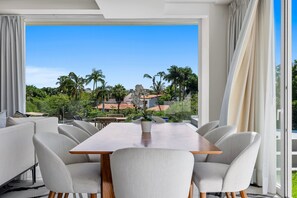 A dining area with a large table and chairs, a view of a building with palm trees, and a clear sky. - Quinta San Miguel alberca y playa 5 min (Nuevo Nayarit)