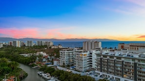 A coastal cityscape with modern buildings, a marina, and a view of the sea and mountains. - Quinta San Miguel alberca y playa 5 min (Nuevo Nayarit)