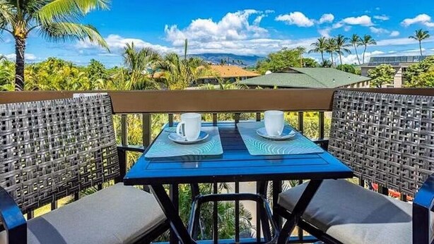Uma mesa com duas chávenas e pires brancos, toalha de mesa azul e cadeiras de vime.