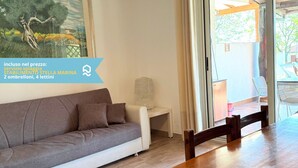A modern living room with a sofa, a dining table, and a view of the outdoors. - VIVA2 - Numana, four-room apartment in villa with swimming pool (Numana)