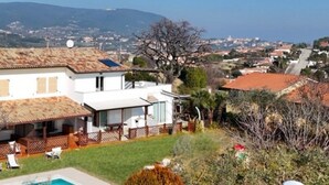 A two-story house with a pool, a fenced patio, and a view of a town and mountains in the distance. - VIVA2 - Numana, four-room apartment in villa with swimming pool (Numana)