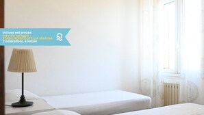 A hotel room with two beds, a nightstand, a lamp, and a window with curtains. - VIVA2 - Numana, four-room apartment in villa with swimming pool (Numana)