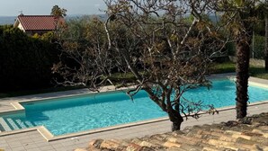 A swimming pool with a tiled deck, surrounded by trees and a house in the background. - VIVA2 - Numana, four-room apartment in villa with swimming pool (Numana)